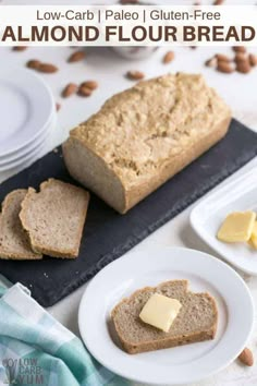 two slices of bread on plates with butter and almonds in the background, along with another loaf of bread