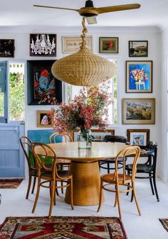 a dining room table surrounded by chairs and pictures on the wall above it with a ceiling fan