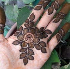 a person's hand with hennap on it and leaves in the background