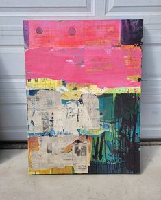 an abstract painting is displayed in front of a garage door, with the colors pink, yellow and blue