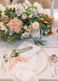 the table is set with silverware, flowers and napkins for an elegant dinner