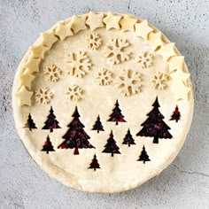 an uncooked pie with snowflakes and trees on it