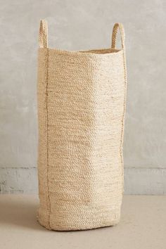 a large woven basket sitting on top of a floor next to a white brick wall