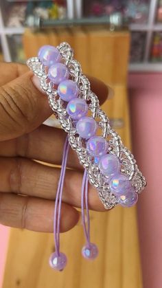 a hand holding a purple bracelet with beads