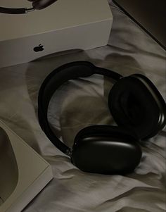 an apple headphones sitting on top of a bed next to a box and remote control