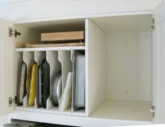 an open cabinet filled with dishes and utensils on top of a white counter