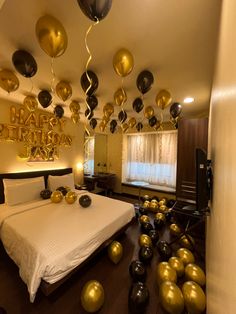 a bedroom decorated in gold and black with balloons floating from the ceiling to the bed