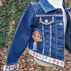 The Bubble Guppies Denim Jacket is perfect for a special occasion. Made from lightweight denim, this custom jean jacket includes a special Bubble Guppies theme, making it the perfect gift for a birthday. These jackets run TRUE TO SIZE. Please note that jackets are personalized and made to order. They will not always be exact replicas. Denim color may vary. Cute Fitted Denim Jacket With Pockets, Cute Fitted Blue Denim Jacket, Spring Denim Jacket For Playtime, Long Sleeve Denim Jacket For Playtime, Denim Jacket Customized, Bubble Guppies Characters, Customized Denim, Jacket Customized, Customised Denim Jacket