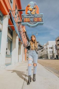 a woman standing on the sidewalk in front of a building with a sign that says, mamama's music hall of fame