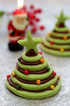 green christmas tree shaped cookies sitting on top of a white tablecloth with candles in the background