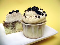 two cupcakes with white frosting and chocolate chips on top sit on a plate