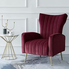 a red chair sitting on top of a white rug next to a table with a candle