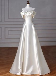 a white wedding dress on a mannequin in front of a gray wall and wooden floor