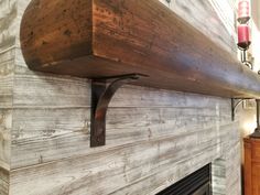 a wooden shelf above a fire place with a candle on the wall next to it