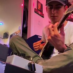 a young man sitting on top of a chair holding a guitar picker in his right hand