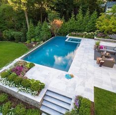 an aerial view of a swimming pool surrounded by greenery and flowers in the backyard