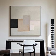 an abstract painting hangs above a modern dining room table with two chairs and a bench