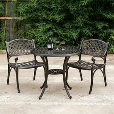 an outdoor table with two chairs and a bottle of wine