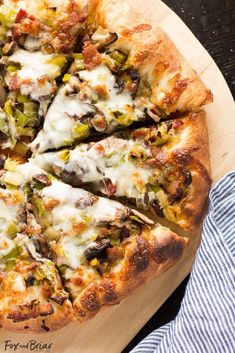 a pizza with several slices missing from it on a cutting board next to a blue and white towel