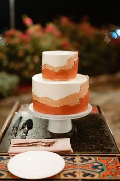 a three tiered cake sitting on top of a table next to a white plate