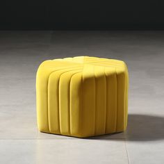 a yellow stool sitting on top of a white floor next to a black and white wall