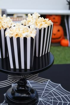 black and white striped cupcakes sitting on top of a cake plate with spider web decorations