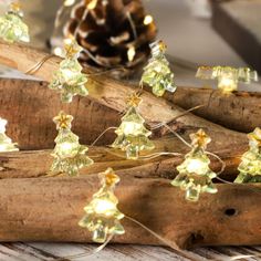 small christmas trees are lit up with lights on wood sticks and pine cones in the background