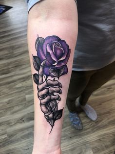 a woman's arm with a purple rose tattoo on the left side of her leg