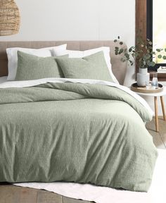 a bed with green sheets and pillows in a room