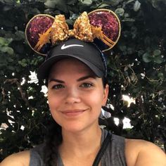 a woman wearing a minnie mouse hat with gold sequins on it's ears