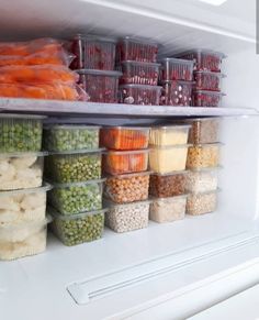 an open refrigerator filled with lots of food and veggies in plastic bins