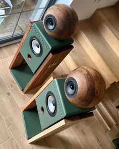 two wooden speakers sitting on top of each other in front of a glass window and wood flooring