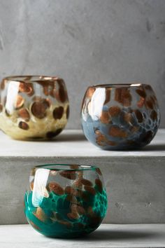 three vases sitting on top of a shelf next to each other in different colors