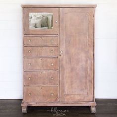 an old wooden armoire with drawers and doors on the bottom, in front of a white wall