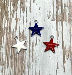 three red, white and blue star charms sitting on top of a wooden table next to each other