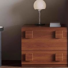 a lamp on top of a wooden dresser next to a wall with a white light