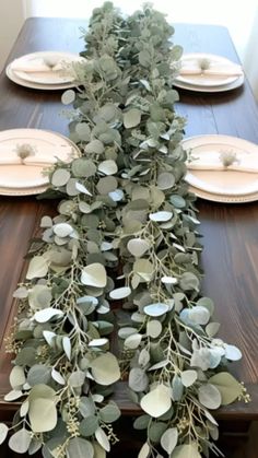 the table is set with plates and greenery