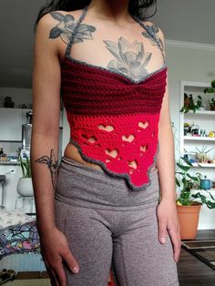 a woman wearing grey pants and a red top with crocheted hearts on it