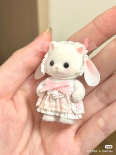 a small white teddy bear wearing a pink dress and bow on it's head