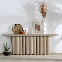 a table with some plants and pictures on it next to a potted plant in a vase