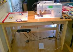 a sewing machine sitting on top of a wooden table next to a bag with an applique