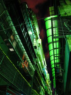 an alleyway at night with neon lights and balconies on the building's sides