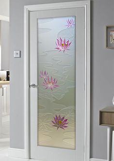 a glass door with pink flowers on it in a white room next to a table