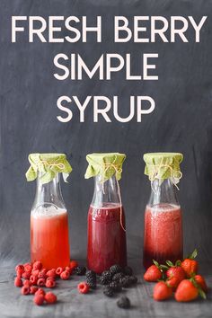 three bottles filled with liquid next to berries and raspberries