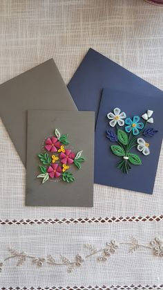 three cards with flowers on them sitting on a table