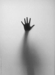 a person's hand in the fog with their shadow on the wall behind them