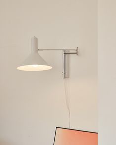 a laptop computer sitting on top of a desk next to a wall light and lamp