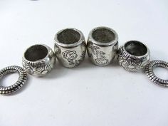 five silver beads with designs on them sitting next to each other and one has two rings around it