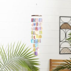 a multicolored wind chime hanging from a ceiling in a room with potted plants