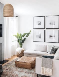 a living room filled with white furniture and pictures on the wall above it's fireplace